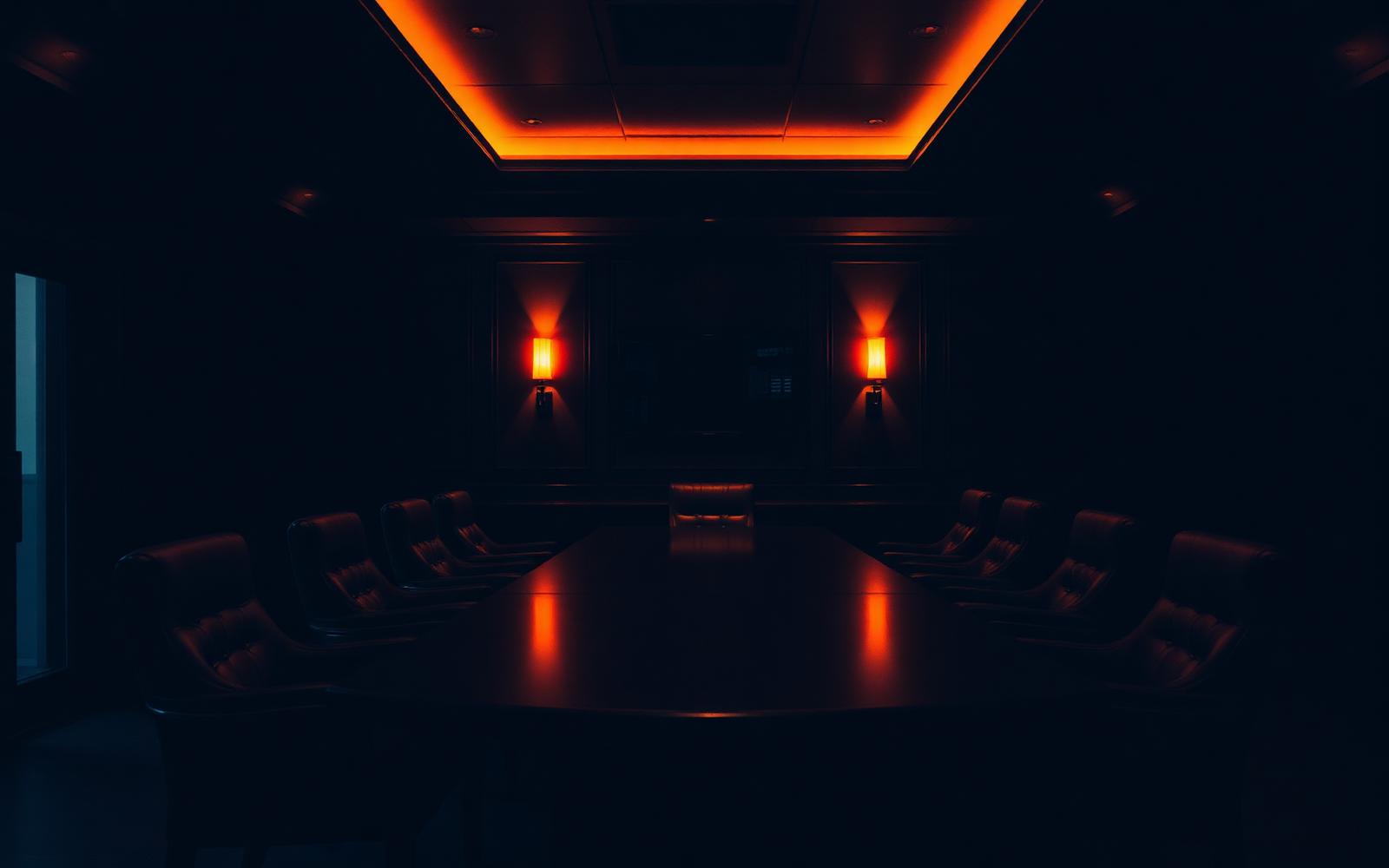 A dimly lit executive boardroom with warm amber light