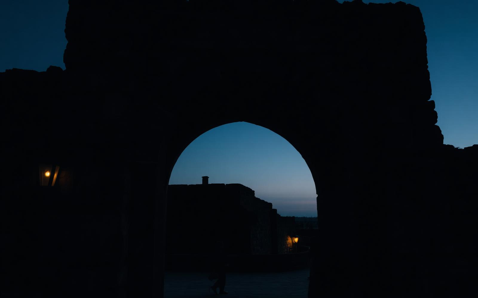 An ancient stone archway silhouetted at dusk