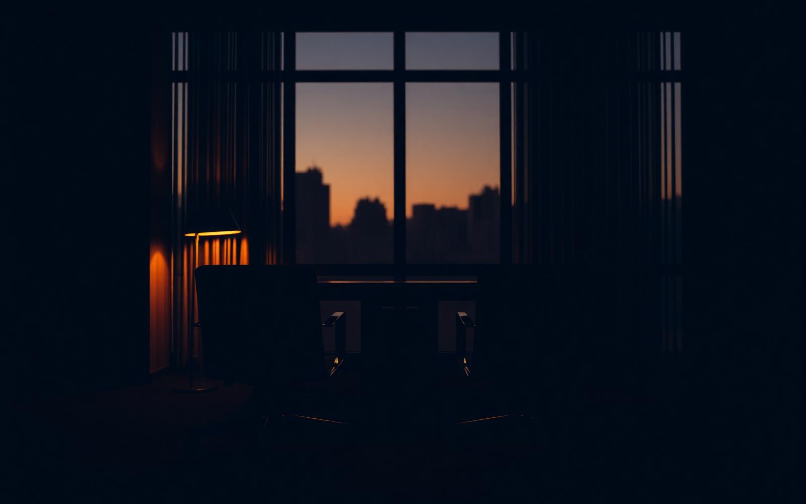 Two empty chairs facing each other in a quiet executive office at dusk, warm amber lamplight against deep charcoal tones